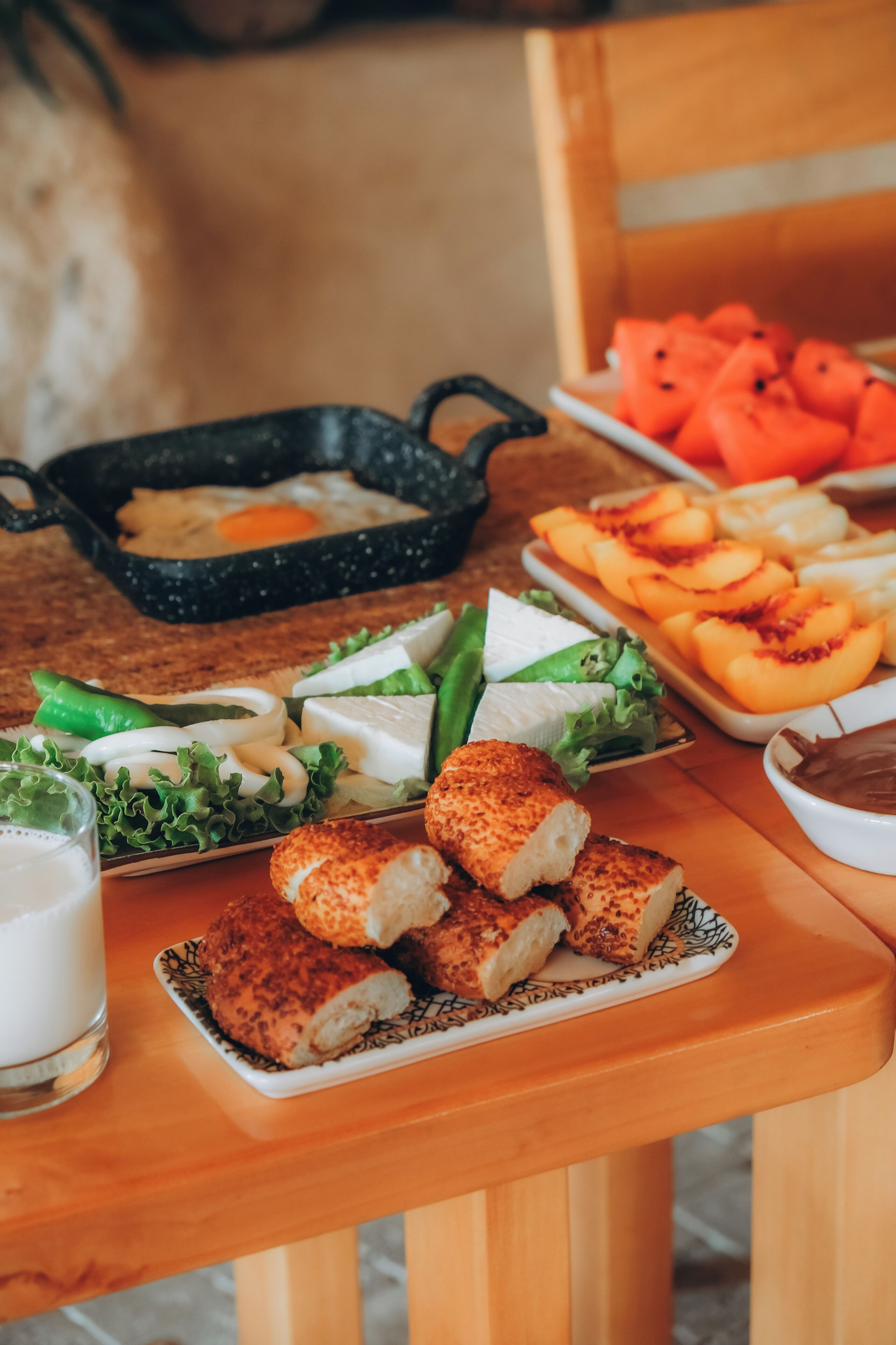 Une table en bois sur laquelle on trouve divers aliments, notamment une assiette de fromage, un bol de soupe et un plateau de fruits coupés.