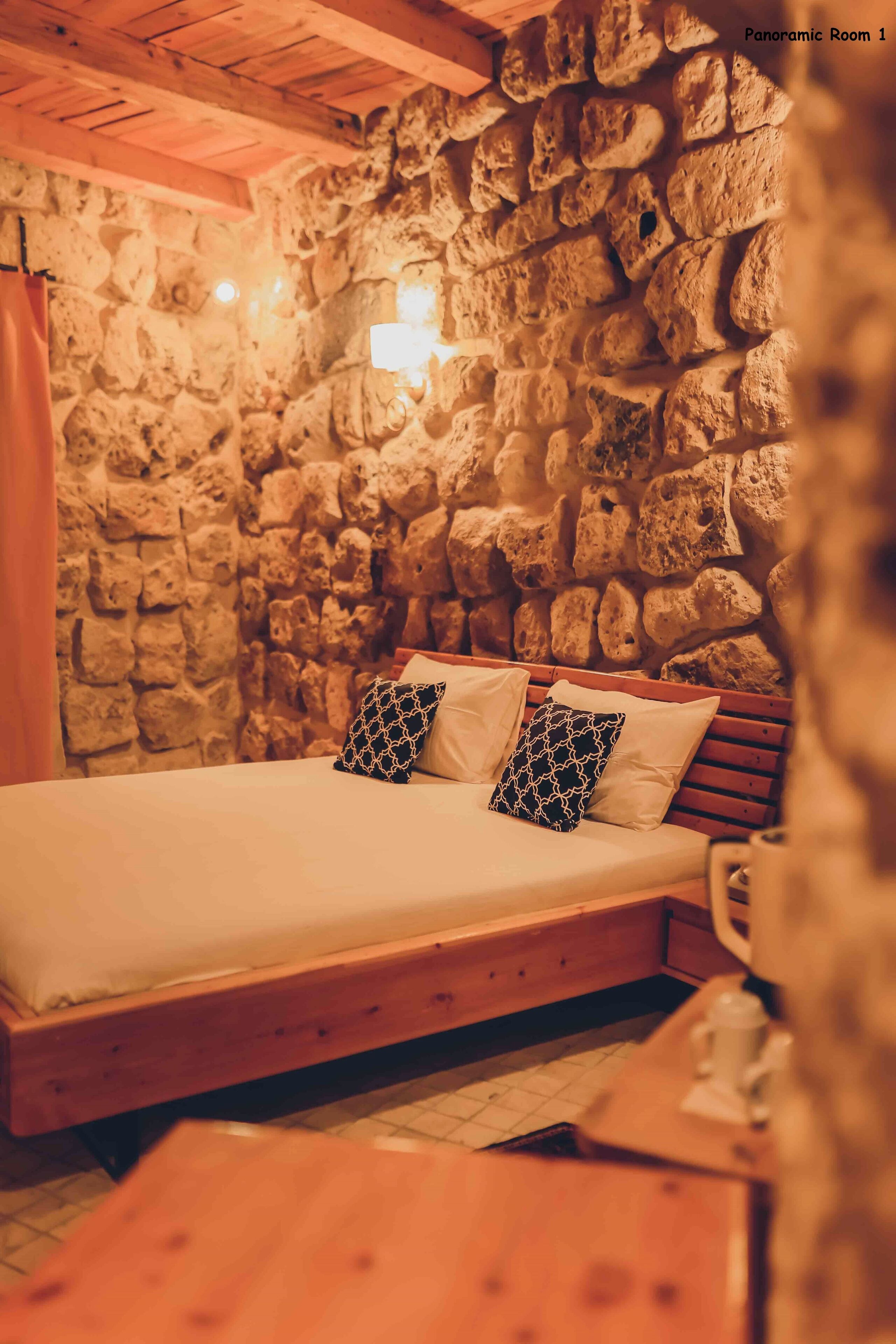 A cozy room with a stone wall, wooden bed, and a nightstand.