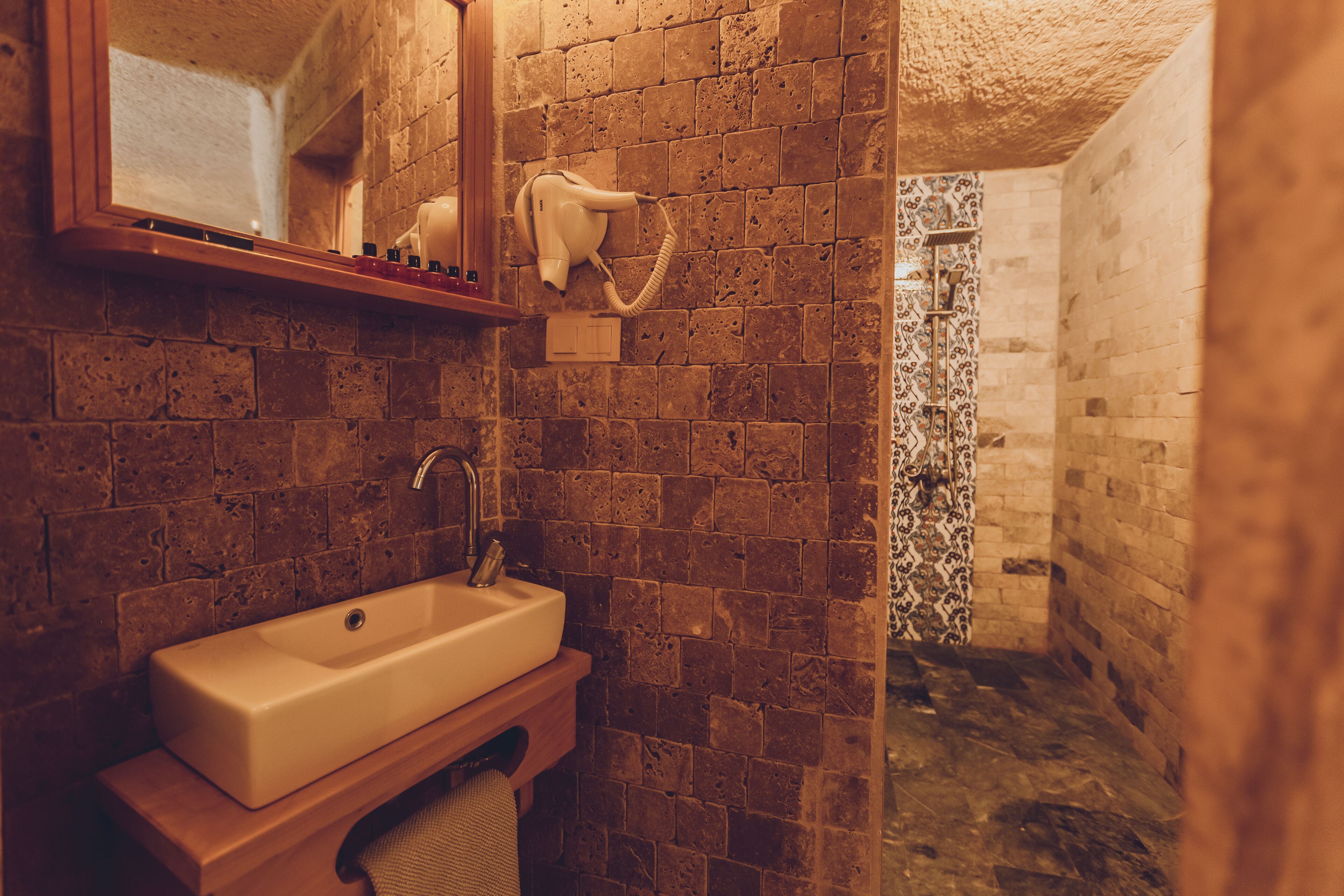 Une salle de bain équipée d’un lavabo, d’un miroir et d’un sèche-cheveux fixés au mur.