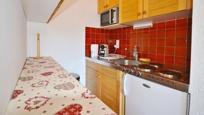 A kitchen with wooden cabinets, a microwave, a sink, and a refrigerator.