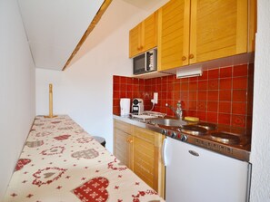 Uma cozinha com armários de madeira, micro-ondas, pia e geladeira.