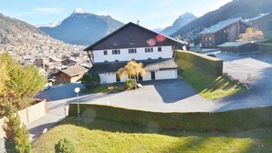 A two-story building with a sloped roof, a small attached garage, and a paved driveway.