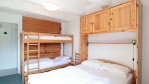 Une chambre avec un lit superposé, dotée d’une tête de lit en bois et d’un lit inférieur.