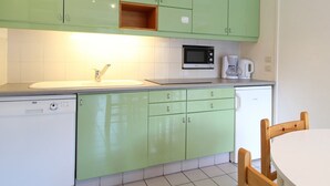 Une cuisine avec des meubles de couleur verte, un four à micro-ondes, une machine à café et un lave-vaisselle.