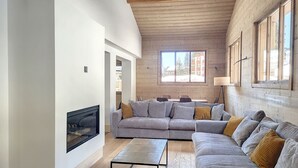 Una sala de estar moderna con un sofá modular, chimenea y ventanas grandes.