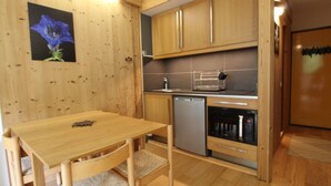 Una cucina compatta con mobili in legno, lavastoviglie e un piccolo frigorifero.