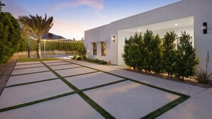 A modern building with a paved driveway, landscaped garden, and a mountain in the background. - Pickleball Court | Pool | Hot Tub (Palm Springs)