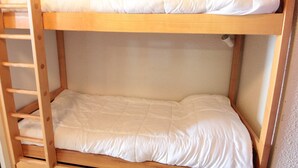 A bunk bed with a wooden frame and white bedding.