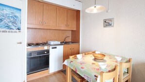 A compact kitchen with wooden cabinets, a built-in oven, and a small dishwasher.