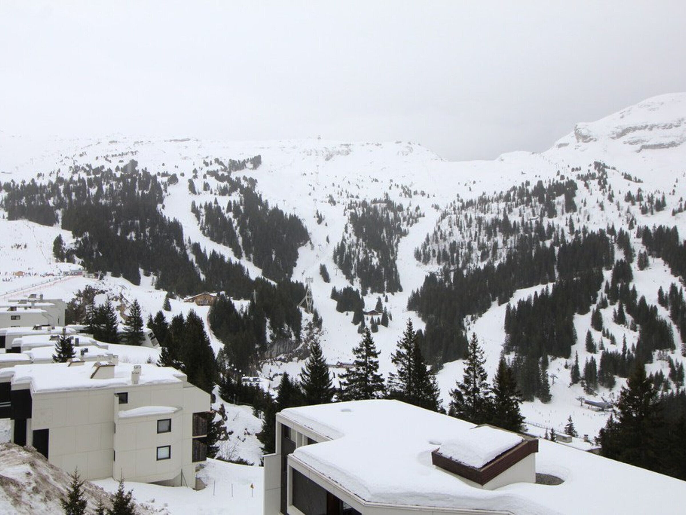 Un paysage montagneux enneigé, avec des bâtiments au premier plan.