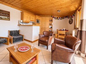 A cozy living room with wooden furniture, a dining area, and a kitchen with wooden cabinets.