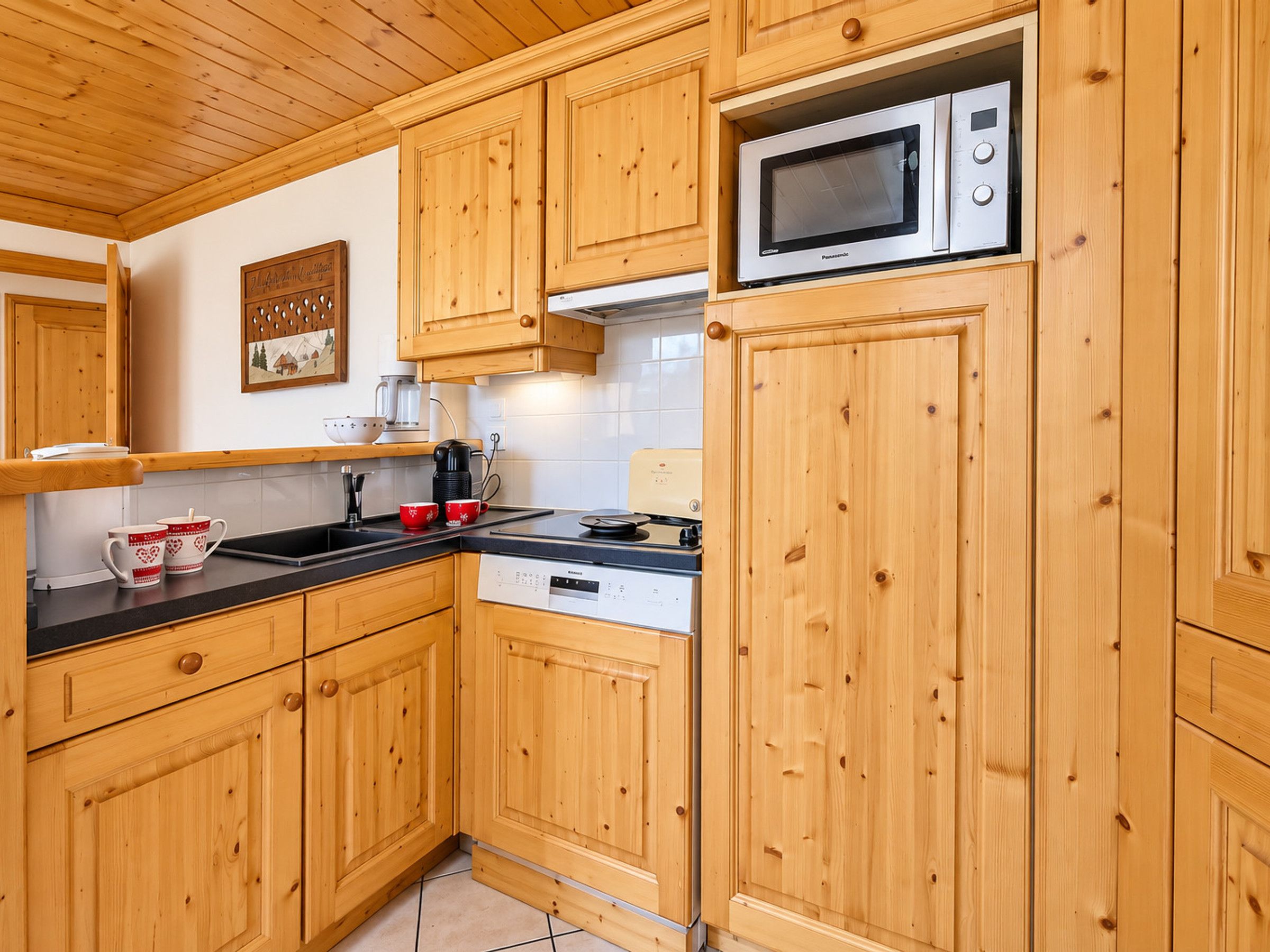 A kitchen with wooden cabinets, a microwave, a coffee maker, and a kettle.
