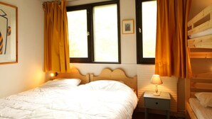 Un dormitorio con una cama, una mesita de noche con lámpara y una ventana con cortinas.