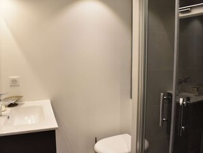 Um banheiro moderno com pia branca, box de vidro e vaso sanitário.