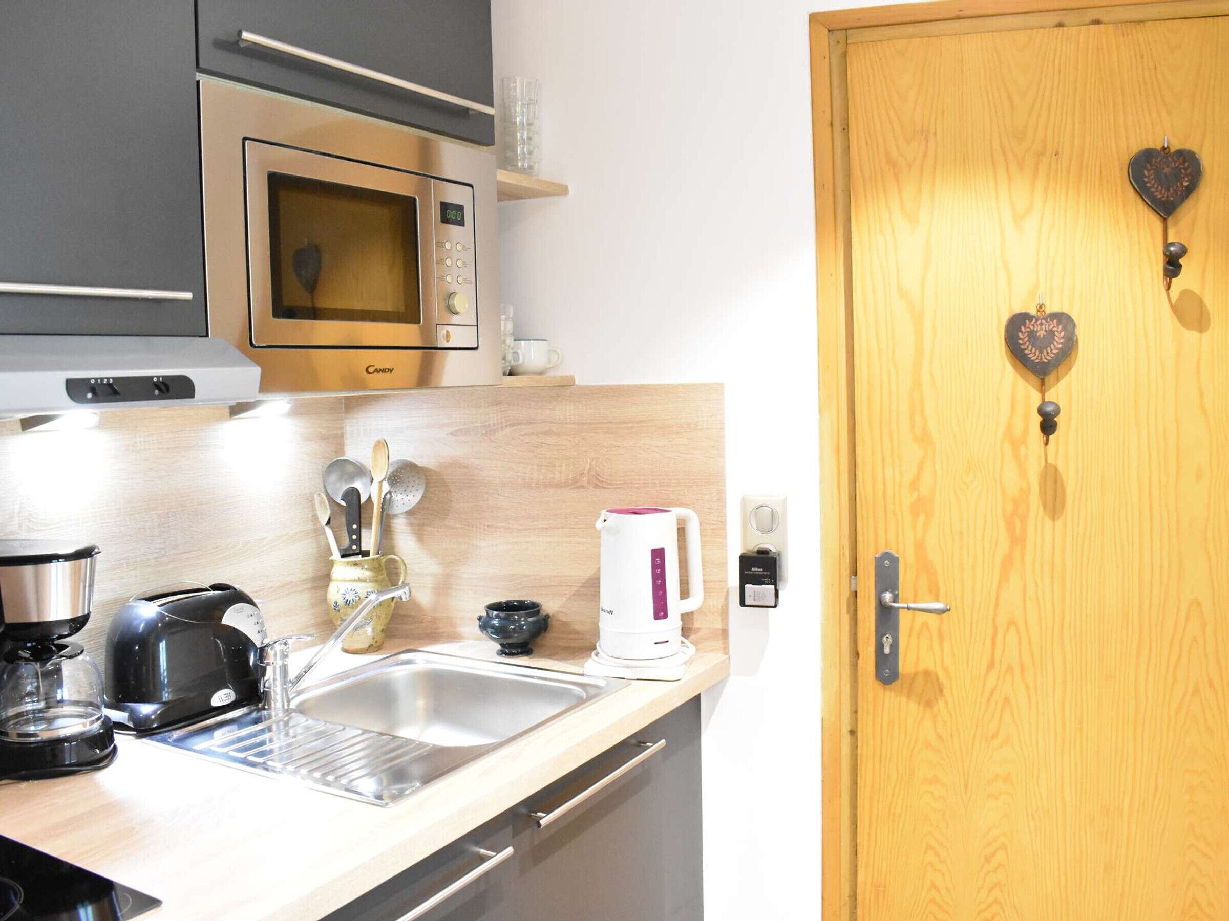 A kitchen with a microwave, coffee maker, and sink.