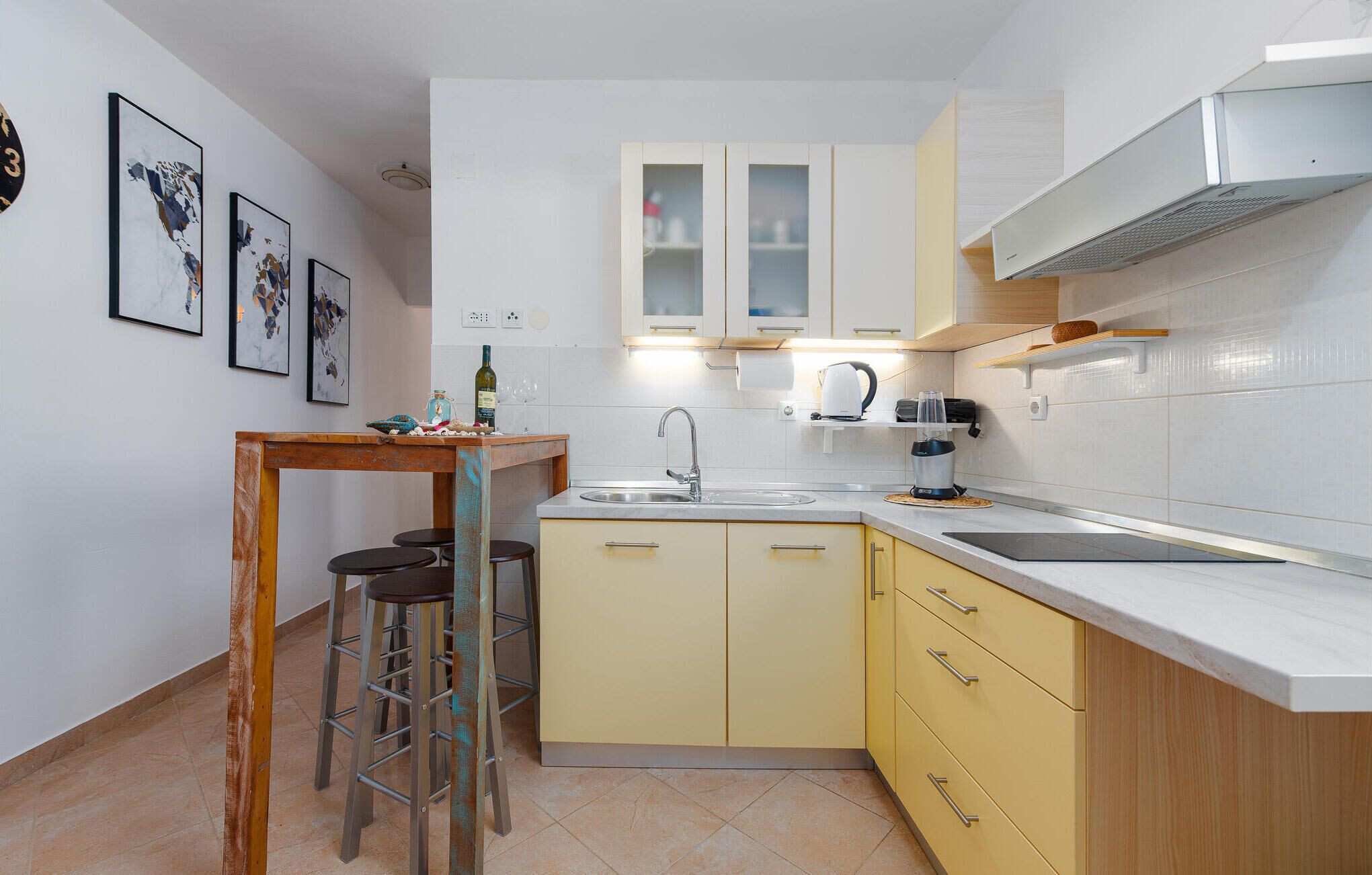 Una cocina compacta con un lavamanos, un pequeño comedor y un taburete de bar.