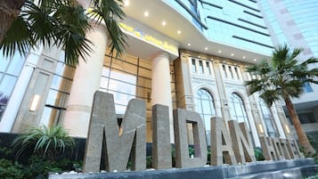 La entrada de un hotel con grandes letras de piedra que dicen "MIDAN HOTEL" y un edificio moderno al fondo.