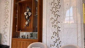 A spacious lobby with a wooden reception desk, two armchairs, and a decorative wall with geometric patterns. - Midan Hotel (Makkah)
