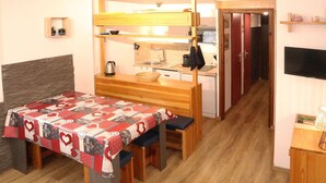 A compact room with a bed, a small kitchenette, and a TV.