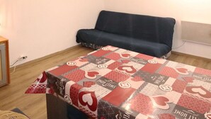 A small room with a sofa and a table covered with a patterned tablecloth.