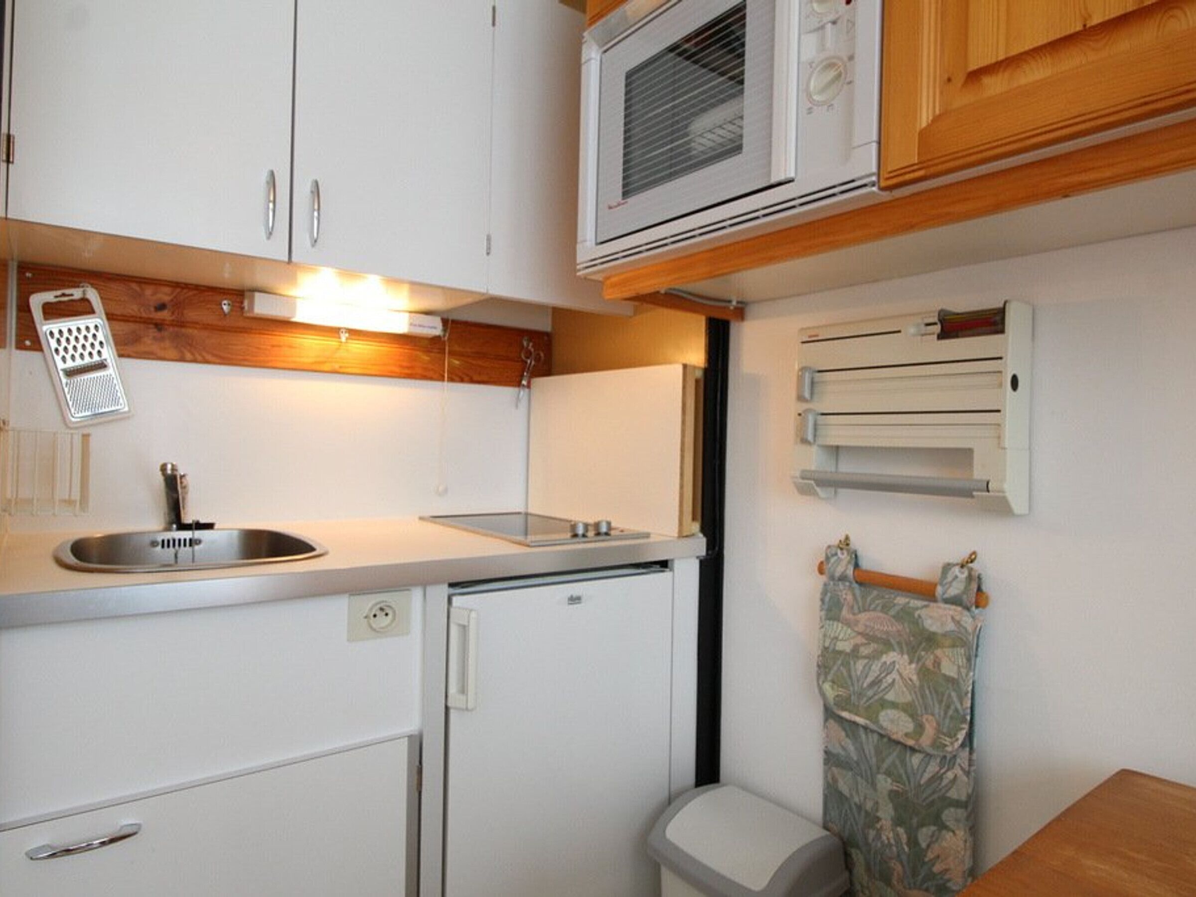 A compact kitchenette with a sink, microwave, and small refrigerator.