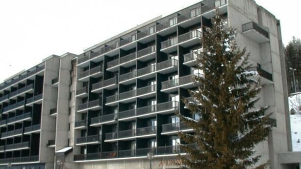 Ein mehrstöckiges Gebäude mit moderner Architektur, das eine Reihe von Balkonen und einen zentralen Eingang aufweist.