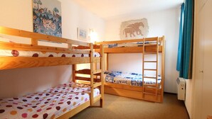 Ein Schlafzimmer mit Etagenbetten, einer Bettdecke mit Punkten, einem Wandbild mit Zeichentrickfiguren und einer Wandlampe.