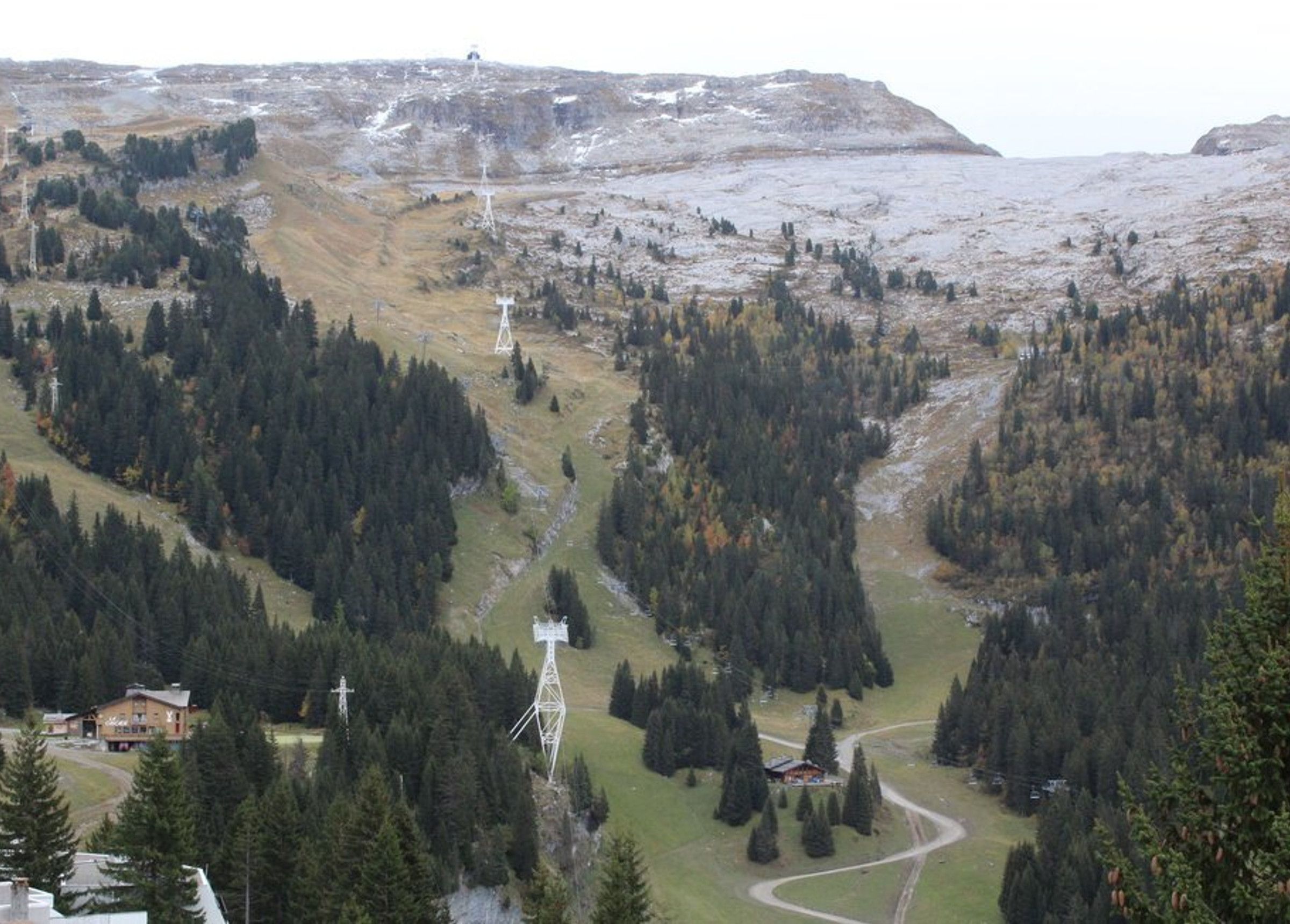 A mountainous landscape with dense forests, winding roads, and several utility towers.