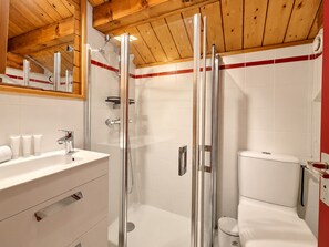 A modern bathroom with a glass-enclosed shower, a white sink with toiletries, and a toilet. - Méribel Chalet: Ski-in/Ski-out, spacious, bright with fireplace (Méribel)