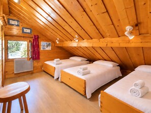 A wooden cabin with three beds, a window with curtains, and a radiator. - Méribel Chalet: Ski-in/Ski-out, spacious, bright with fireplace (Méribel)