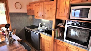 A kitchen with wooden cabinets, a stainless steel refrigerator, a microwave, and a stove.