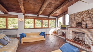Ein geräumiger Wohnbereich mit Kamin aus Backstein, großen Fenstern und einer gemütlichen Sofagarnitur.