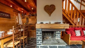 Un acogedor interior de cabaña con chimenea de piedra, una mesa de comedor de madera y un sofá rojo.