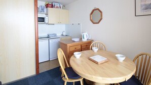 A compact kitchen with a microwave, sink, and cabinets. There is a dining table with chairs and a mirror on the wall. - Cozy Studio for 5 in Sagittaire Residence, Near Slopes, South-Facing Balcony (Flaine)
