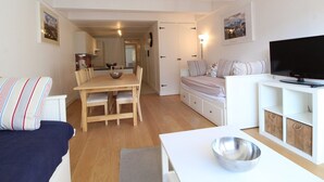Een knus woongedeelte met een eethoek, een bank, een televisie en een kitchenette.