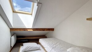 Una stanza piccola e accogliente con due letti singoli, una finestra a lucernario e travi a vista in legno.