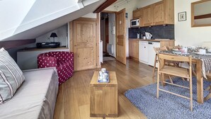 Un ambiente compatto con zona notte soppalcata, angolo cottura e sala da pranzo.