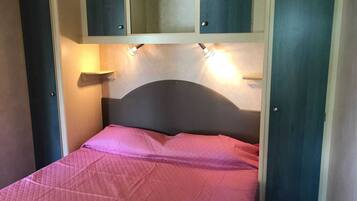 Ein Bett mit Kopfteil, einer rosafarbenen Bettdecke und zwei Wandleuchten.