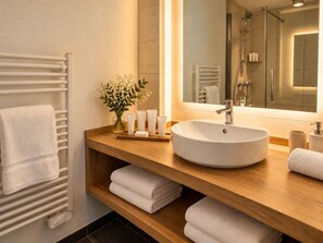 A modern bathroom with a large sink, a mirror, a towel rack, and a shower area.