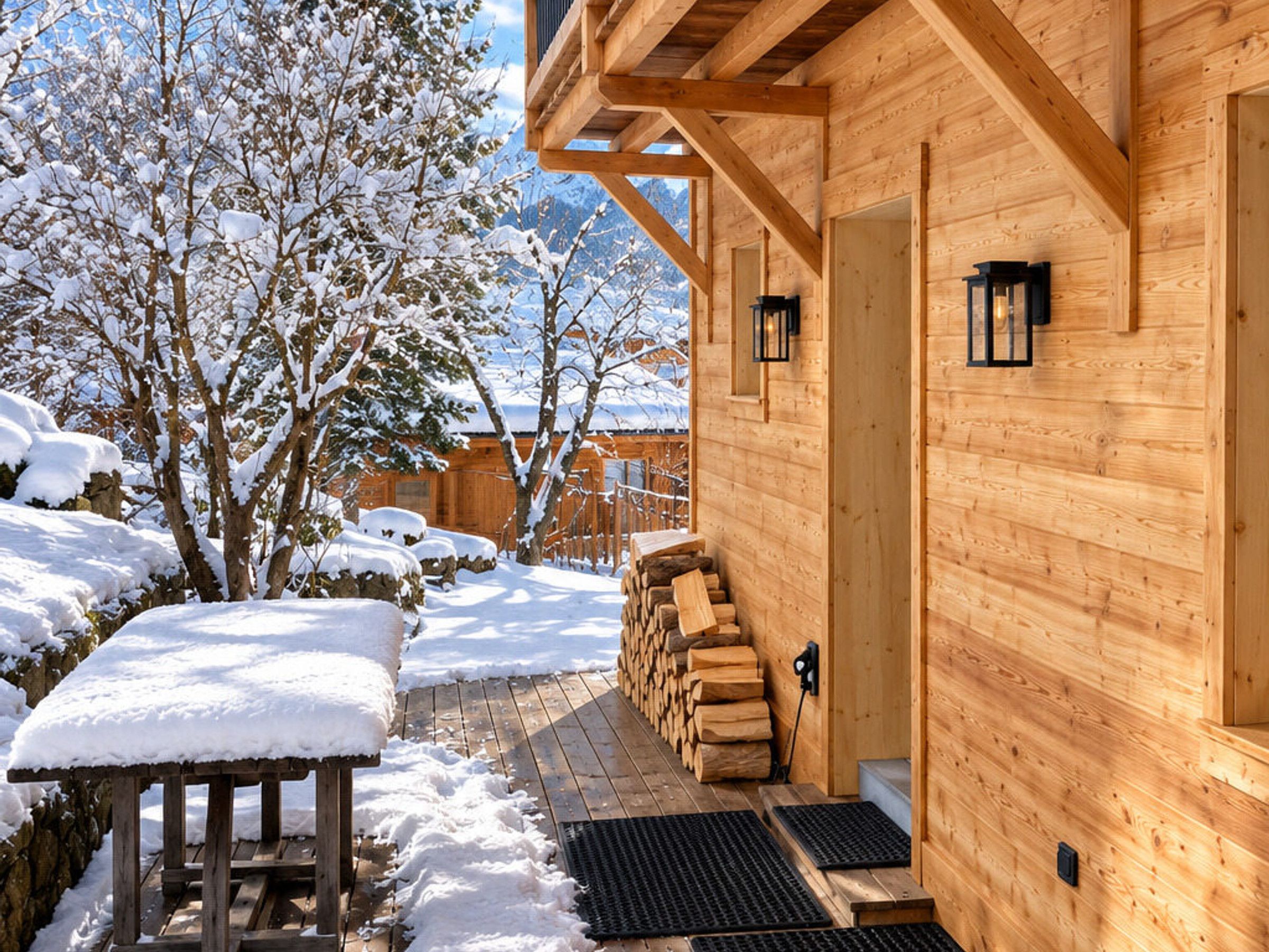 Une cabane en bois avec une terrasse enneigée, une pile de bois de chauffage et un banc en bois.