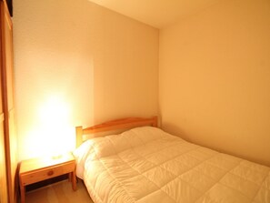 A small, single-bed room with a wooden headboard, a bedside table, and a nightstand. - Renovated Studio for 5 in Flaine Forest, Close to Slopes and Shops (Flaine)