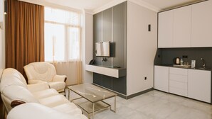 Una sala de estar moderna con un sofá, una mesa de centro, un televisor y una cocina con armarios y encimera.