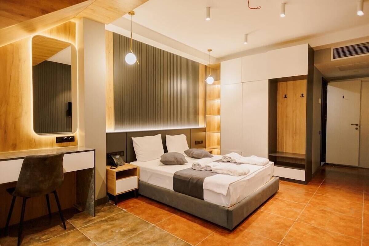 A modern bedroom with a bed, bedside tables, a desk, and a mirror.