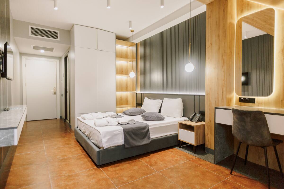 A modern bedroom with a bed, bedside table, and a desk with a chair.