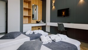 Una habitación de hotel moderna con dos camas, televisión, escritorio y espejo.