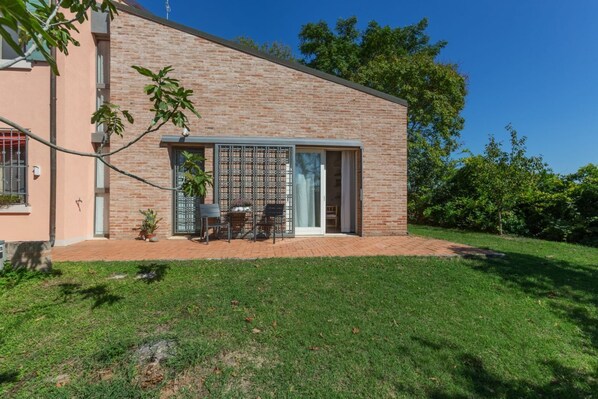 Un bâtiment moderne à deux étages, doté d’une façade en briques, d’un patio couvert avec des meubles d’extérieur et d’une grande porte-fenêtre coulissante.