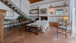 Una habitació àmplia amb un llit, una taula de fusta, cadires, una escala i prestatgeries amb diversos objectes.