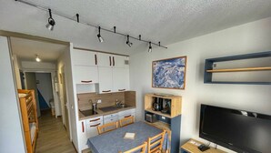 A compact living space with a kitchenette, dining area, and a TV. - Cozy Studio for 5, Near Ski Lift and Shops, South-Facing Balcony, Flaine Forest - Doris Residence (Flaine)