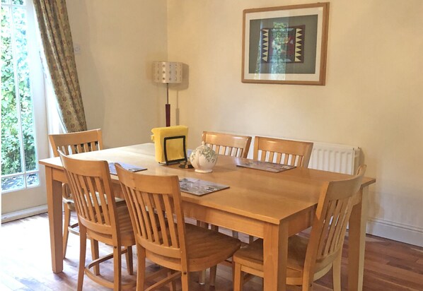 Un comedor con una mesa y sillas de madera, una lámpara y un cuadro en la pared.