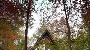 A cabin with a large balcony, surrounded by trees.